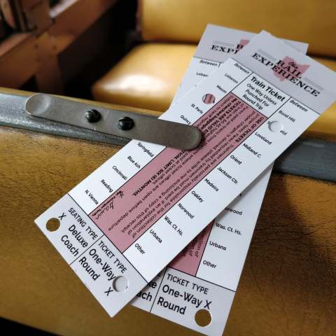 Two train tickets clipped on a yellow seat inside a vintage train.