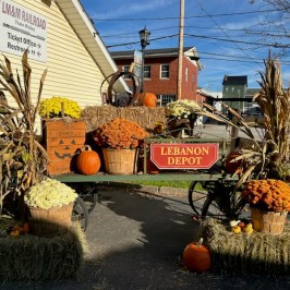 Fall-themed display at Lebanon Depot with pumpkins and flowers on a cart.