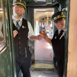 two people wearing train conductor uniforms on a train
