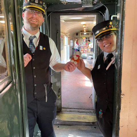 two people wearing train conductor uniforms on a train