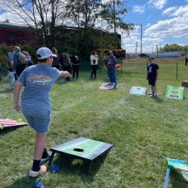 a group of people that are standing in the grass playing yard games