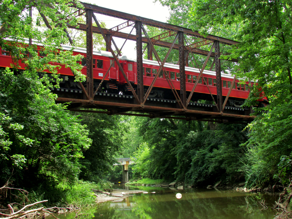 LACKAWANNA COACHES – CARS 101-104 a train crossing a bridge over a river in a forest