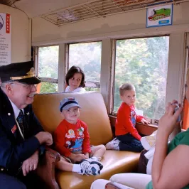 a group of people sitting inside a train with a train conductor