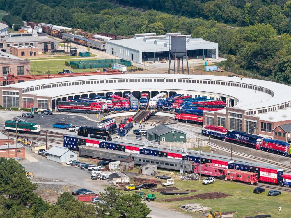 Aerial view of a train yard with numerous trains and a roundhouse.