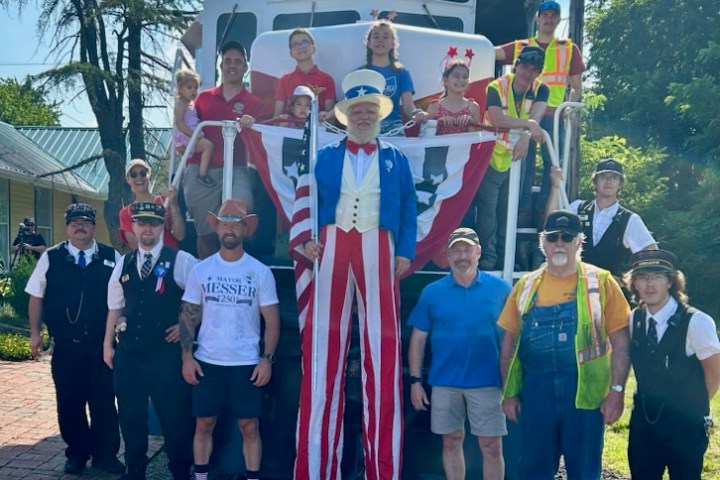 Group photo with train, people in patriotic costumes, and conductor uniforms.