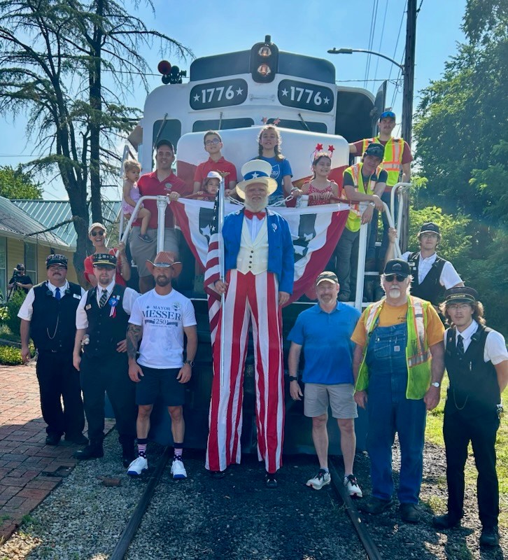 Group photo with train, people in patriotic costumes, and conductor uniforms.